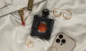 Elegancka kompozycja z flakonem perfum **Black Opium 100ml**, złotą szminką, biżuterią i telefonem na jedwabiu.