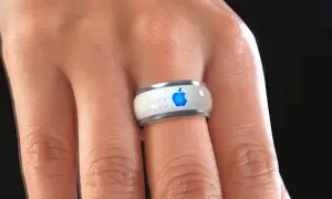 Bague connectée Apple, blanche avec logo bleu lumineux, portée au doigt.