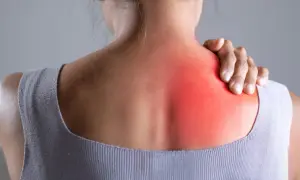Donna con mano sulla spalla, evidenziata un'area rossa che indica dolore in mezzo alle scapole.