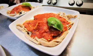 Sagne torte fatte in casa con sugo di pomodoro fresco e basilico, servite in un piatto bianco.