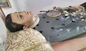 Relikwie św. Szarbela w dzień 9 nowenny. Figurka leży na ozdobnej poduszce, z krzyżem i relikwiarzem na piersi.