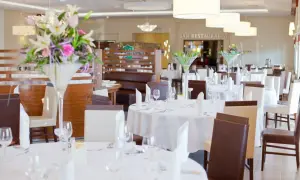 Elegancka sala bankietowa w austerii niemczańskiej, nakryte stoły z kwiatami i białymi obrusami, gotowe na przyjęcie gości.