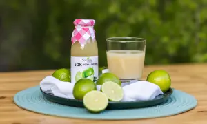 Butelka soku z limonki i szklanka orzeźwiającego napoju, otoczone świeżymi owocami. Odkryj sok z limonki właściwości!