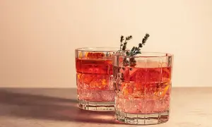 Dwa drinki z plasterkami pomarańczy i gałązkami ziół w szklankach z grubego szkła. Idealne na letni wieczór, dodają klimatu.