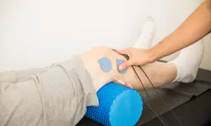 Rehabilitacja kolana: elektrostymulacja i wałek do masażu.