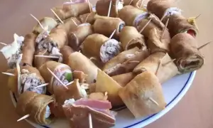Assiette de crêpes roulées garnies, parfaites pour un apéro convivial. Des bouchées savoureuses prêtes à être dégustées.