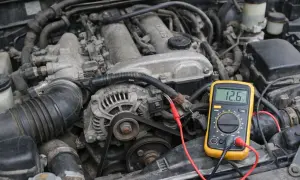 Un multimètre jaune connecté à un alternateur de voiture pour tester son fonctionnement. La lecture indique 12.6V.