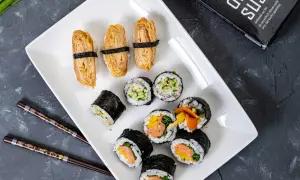 Pyszne domowe sushi przepis na talerzu: nigiri z omletem tamago, rolki z łososiem i warzywami, ogórkiem i sezamem.