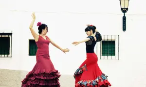 Dos mujeres bailan flamenco, con faldas rojas y volantes. Una lección de baile flamenco para principiantes.