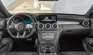 Interiörbild på en Mercedes C-klass med digital instrumentpanel och infotainmentsystem. Kolfiberdetaljer och röda sömmar antyder en sportig modell, men det finns inget uppenbart problem.