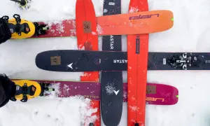 Skier mit gelben Tourenschuhen und Skiern in verschiedenen Farben, darunter ein schwarzer Ski mit der Aufschrift "black crows navis freebird".