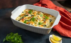 Herzhafte Lachs Spinat Lasagne, goldbraun überbacken, garniert mit frischer Petersilie. Dazu Zitronenspalten.