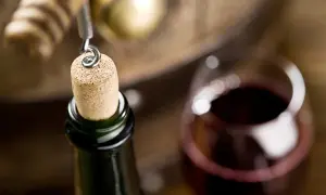 Korek w butelce wina, kieliszek i beczka. Zastanawiasz się, ile może stać otwarte wino? Czasem warto poczekać.