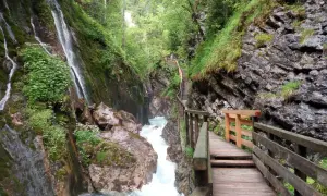 Holzstege führen durch die Klamm Berchtesgaden, vorbei an tosendem Wasser und moosbewachsenen Felsen.