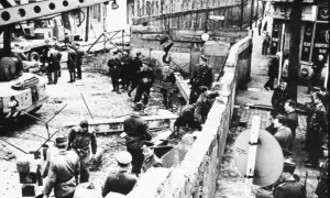 Militär och civila vid Berlinmuren, en scen som kan illustrera kalla kriget tidslinje. En kran lyfter bort delar av muren.
