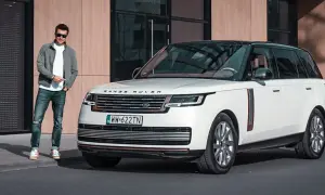 Elegancki mężczyzna obok białego Range Rovera. Sprawdź aktualną range rover cena i dowiedz się więcej o tym luksusowym SUV-ie.