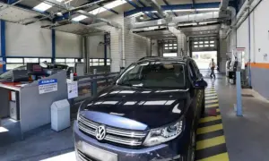 Un coche oscuro en un centro de inspección técnica, listo para pasar la ITV. El personal revisa los papeles.
