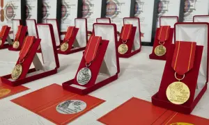 Medale za zasługi dla pożarnictwa w czerwonych etui, gotowe do wręczenia. W tle dokumenty potwierdzające odznaczenia.