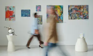 W galerii sztuki, gdzie obrazy zachęcają do kreatywności, jak w muzeum dla dzieci, dwie postacie w ruchu podziwiają abstrakcyjne dzieła.