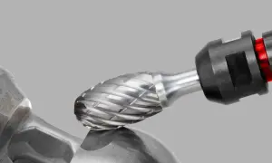 Metalowy frez z nacięciami, zamocowany w uchwycie, zbliża się do metalowego elementu.