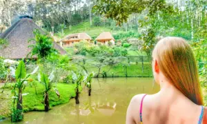 Dziewczyna podziwia tropikalny krajobraz z jeziorem i domkami. Idealne **Madagaskar wakacje**!