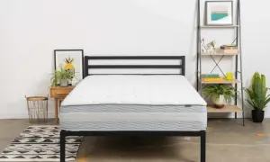 A white and gray mattress on a black metal bed frame. This is one of the mattresses to avoid if you want a good night's sleep.