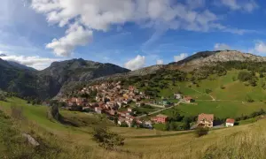 Pueblo de Sotres en los Picos de Europa, ideal para explorar sus rutas. Casas de piedra y tejados rojos entre verdes prados y montañas.