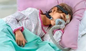 Dziecko śpi z maską CPAP, która pomaga mu oddychać podczas snu, łagodząc bezdech u dziecka.