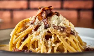 Pyszne spaghetti carbonara, klasyka włoskich przepisów na makaron, posypane parmezanem i chrupiącym boczkiem.