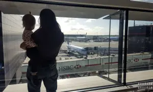 Mama z dzieckiem na rękach patrzy na samoloty. Czas na boarding, przygoda czeka!