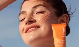 Une jeune femme rayonne sous le soleil, protégeant sa peau avec un fluide solaire. Un rappel : mettre de la crème solaire tous les jours pour une peau éclatante.