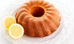 Puszysta babka cytrynowa siostry Anastazji, lekko zarumieniona, z dwoma plasterkami cytryny na ozdobnym talerzu.