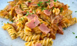 Ein köstlicher Nudelauflauf mit Spiralnudeln, Schinken und Käse, garniert mit Petersilie.