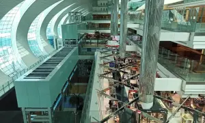 Der Flughafen Dubai innen: ein modernes Einkaufsparadies mit Glas und Stahl. Helle Gänge, Geschäfte und Palmen laden zum Verweilen ein.
