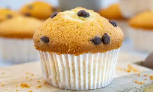 Ein goldbrauner Schoko-Muffin, perfekt für das Muffins Grundrezept. Mehrere Muffins im Hintergrund.