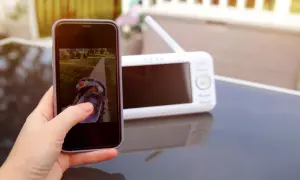 Jak podłączyć kamerę wifi z telefonem? Na ekranie smartfona widać dziecko w wózku, a obok monitor podglądu.