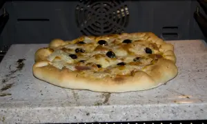 Pizza z oliwkami i serem, wypiekana na kamieniu biscotto w piekarniku.