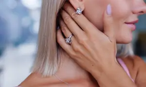Elegancka kobieta z biżuterią: kolczyki i pierścionek z próby srebra 800, ozdobione błyszczącymi kamieniami.
