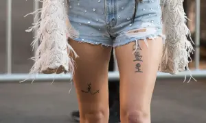 Dwa tatuaże nad kolanem: na jednym udzie linia symbolizująca pocałunek, na drugim seria symboli, w tym róża.
