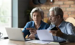Para, mam 60 lat i 10 lat pracy, czy dostanę emeryturę? Zastanawiają się nad tym, analizując dokumenty i dane na laptopie.