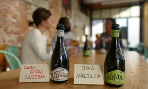 Bottiglie di birra sul tavolo. Una indica "Birra senza glutine", l'altra "Birra analcolica". Attenzione: la birra contiene lattosio.