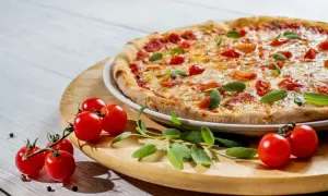 Pyszne ciasto na pizzę z jajkiem, pomidorkami i bazylią, gotowe do podania.