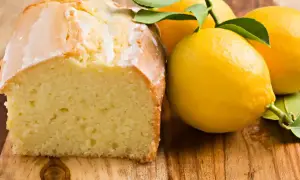 Un délicieux moelleux au citron, avec un glaçage blanc et des citrons frais sur une planche en bois.