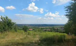 Widok z góry św. Doroty na zieloną dolinę z domami i miastem w oddali. Błękitne niebo z białymi chmurami.