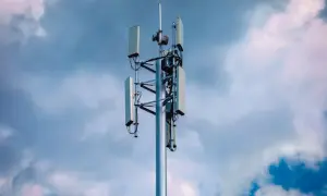 Wieża telekomunikacyjna z antenami, gotowa do obsługi sieci 5G, na tle burzowego nieba.
