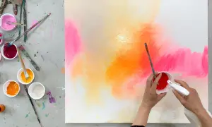 Bunte Farben auf einer Leinwand, bereit zum leinwand bemalen mit kindern. Pinsel und Becher mit Farbe liegen bereit.