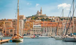 Segelboote im Hafen von Marseille, mit der Basilika Notre-Dame de la Garde im Hintergrund. Hier kann man viel unternehmen!