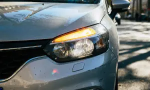Gros plan sur le phare d'une voiture argentée. Le feu de jour est allumé, avec le clignotant orange clignotant.
