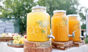 Orzeźwiające drinki na wesele: wielkie słojki z napojami owocowymi, plasterkami cytrusów i miętą, gotowe do podania.