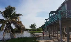 Kobieta na plaży, palmy i domki na palach. Idealne miejsce na belize wakacje.